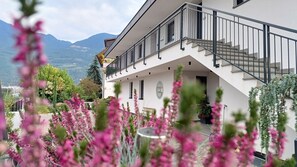 A modern two-story building with a balcony, a staircase, and a view of mountains. - Bike Apartments Curti "Himmelblau" with Sun Terrace & Alpine Views (Pfatten)
