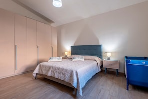 Une chambre à coucher avec un lit, des tables de chevet, une commode et une valise.