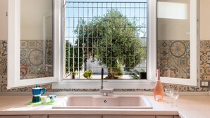 A kitchen with a sink, a window with a view of greenery, and a decorative backsplash.