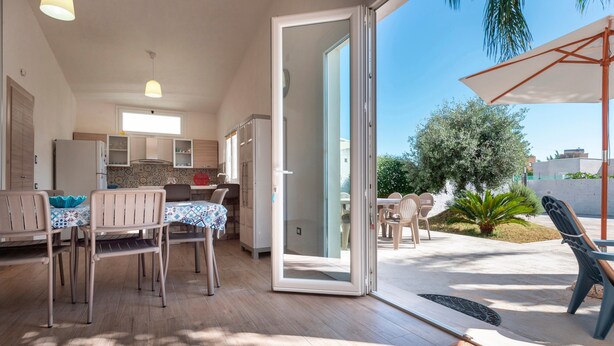 A modern kitchen with a dining area, a sliding glass door to an outdoor patio, and a view of the surrounding area.