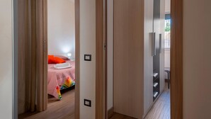 A room with a bed, a wardrobe, and a door leading to another room.