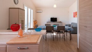 A modern kitchen with a dining area, a TV, and a living space.