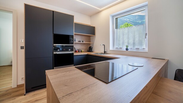 A modern kitchen with a central island, built-in appliances, and a window with a view.