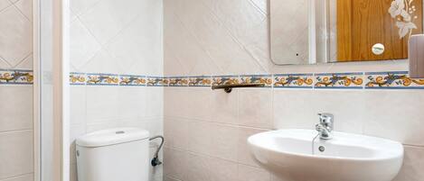A bathroom with a toilet, sink, and a wooden door with a floral design.