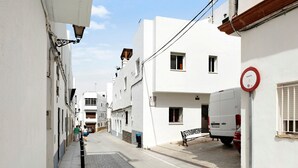 Un vicolo stretto con edifici bianchi, una panchina e un furgone bianco parcheggiato a destra.