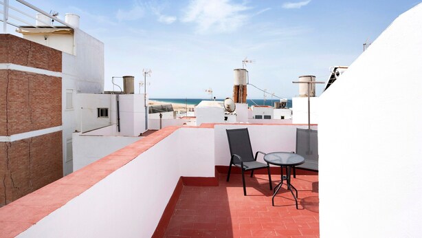 Una terrazza sul tetto con tavolo e sedie, vista sul mare e un muro in mattoni.