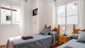 Camera da letto con due letti, un comodino, una lampada e un quadro appeso al muro.