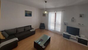 Una sala de estar moderna con un sofá, una mesa de centro, un mueble para televisión y una silla.