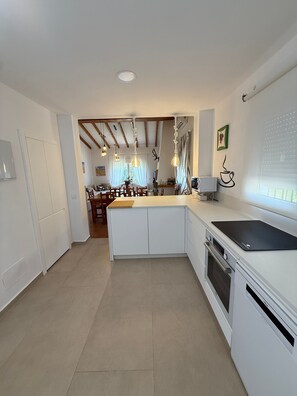 Una cocina moderna con armarios blancos, encimera negra y horno integrado.