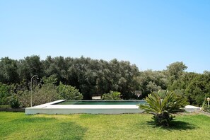 A swimming pool with a concrete deck, surrounded by lush greenery and trees. - Casa Los Alamos with Pool, Renovated Kitchen, Wi-Fi, and Terrace (Vejer)