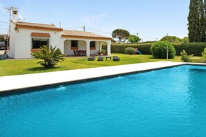 A house with a swimming pool, a patio with chairs, and a well-maintained lawn. - Casa Los Alamos with Pool, Renovated Kitchen, Wi-Fi, and Terrace (Vejer)