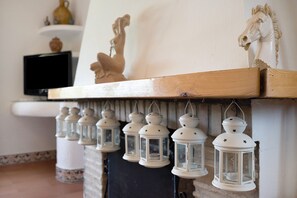 A fireplace with white lanterns hanging above it, a statue of a horse, and a television on a shelf. - Casa Los Alamos with Pool, Renovated Kitchen, Wi-Fi, and Terrace (Vejer)