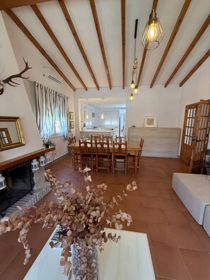 A room with a fireplace, dining table, chairs, and a decorative plant arrangement. - Casa Los Alamos with Pool, Renovated Kitchen, Wi-Fi, and Terrace (Vejer)