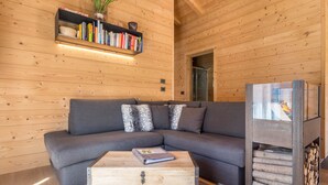 A cozy living room with a grey sectional sofa, a wooden coffee table, a bookshelf, and a fireplace.