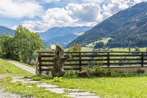 Un paysage montagneux pittoresque avec une clôture en bois, un sentier et le tronc d’un arbre.