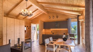 A wooden interior with a dining area, kitchen, and fireplace.