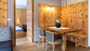Een kamer met houten lambrisering, een bed, een tafel met stoelen en een bank.