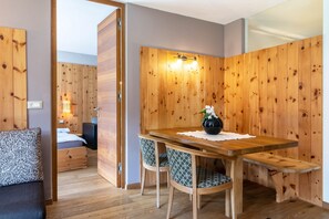 A wooden-paneled room with a bed, a table with chairs, and a bench.