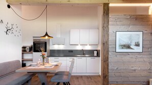 A modern kitchen with white cabinets, a dining table with chairs, and a pendant light. - Holiday Apartment 'Living Lerchna - Beautiful View' with Mountain View, Balconies and Wi-Fi (Maranza)