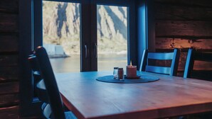 A wooden table with two chairs, salt and pepper shakers, and a candle. - Svinøya Rorbuer (Vagan)