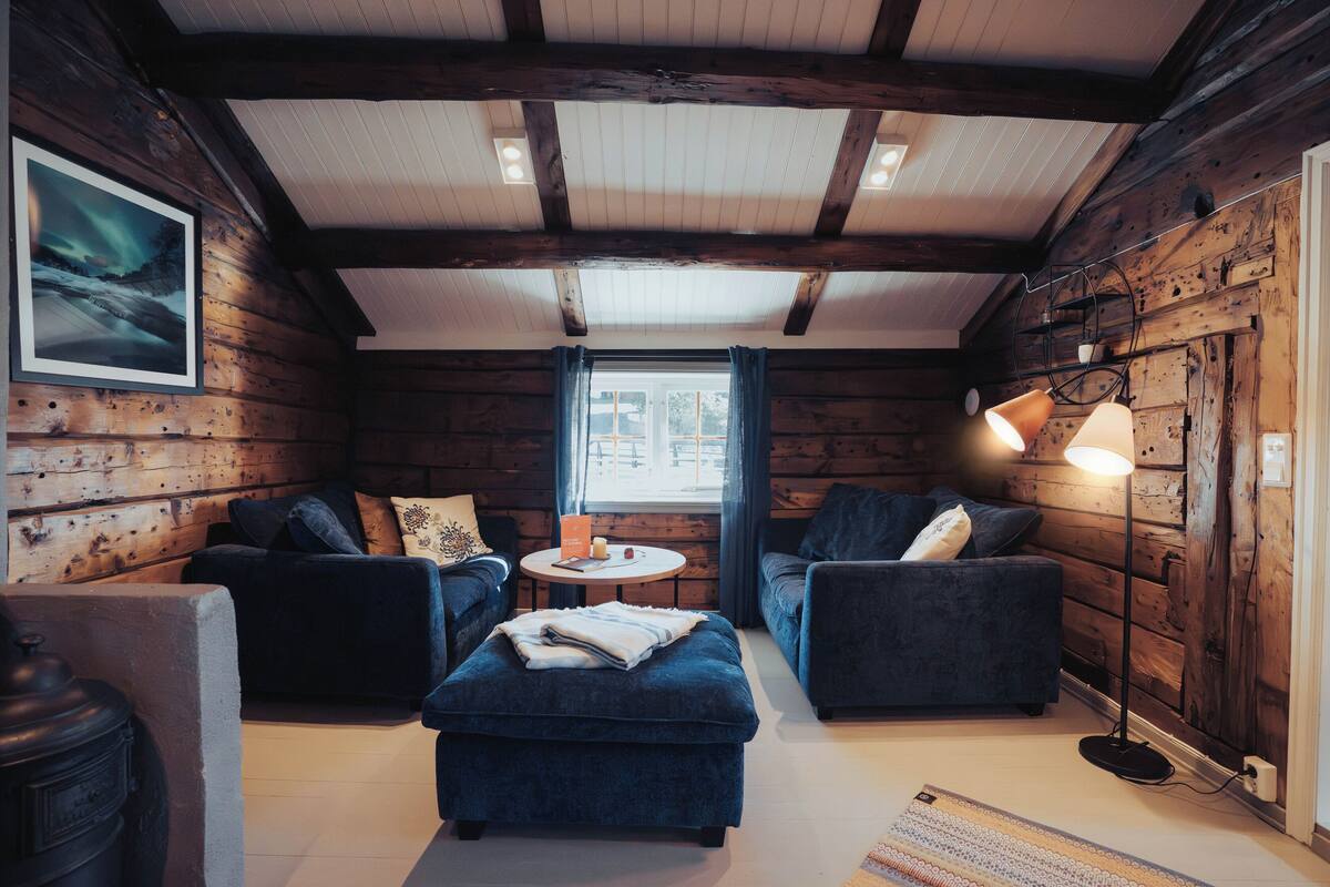 A cozy log cabin interior with two sofas, a small round table, and a lamp.