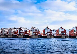 A row of red wooden houses with balconies, connected by wooden walkways over water.
