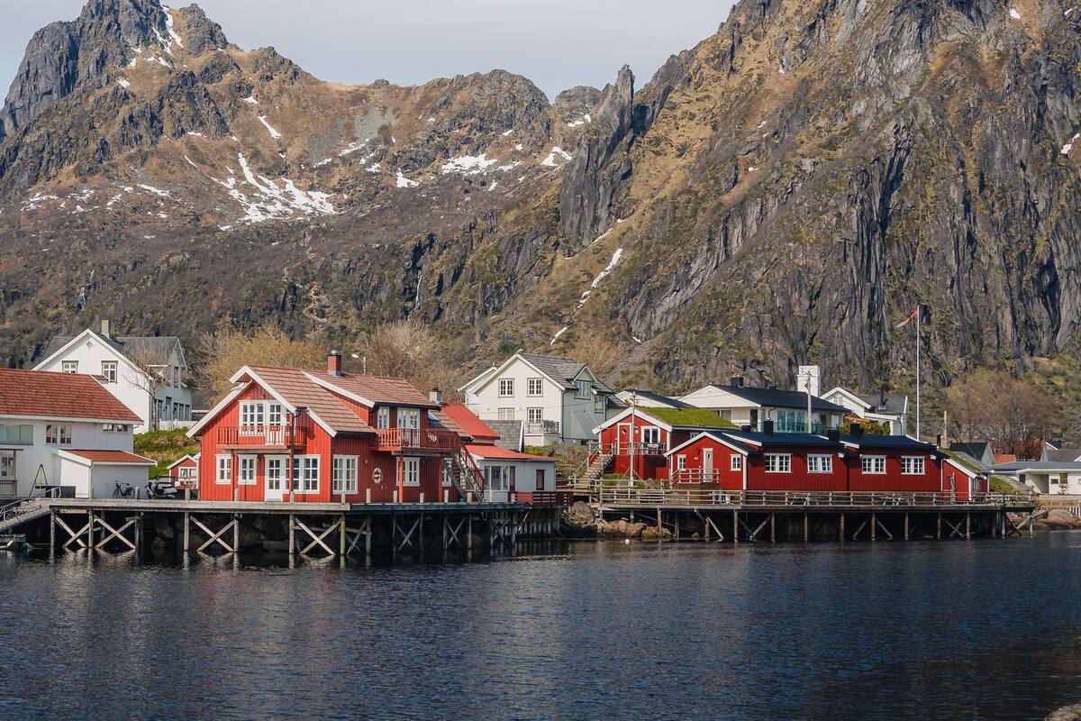 A waterfront property with red and white buildings, a dock, and a mountainous backdrop.