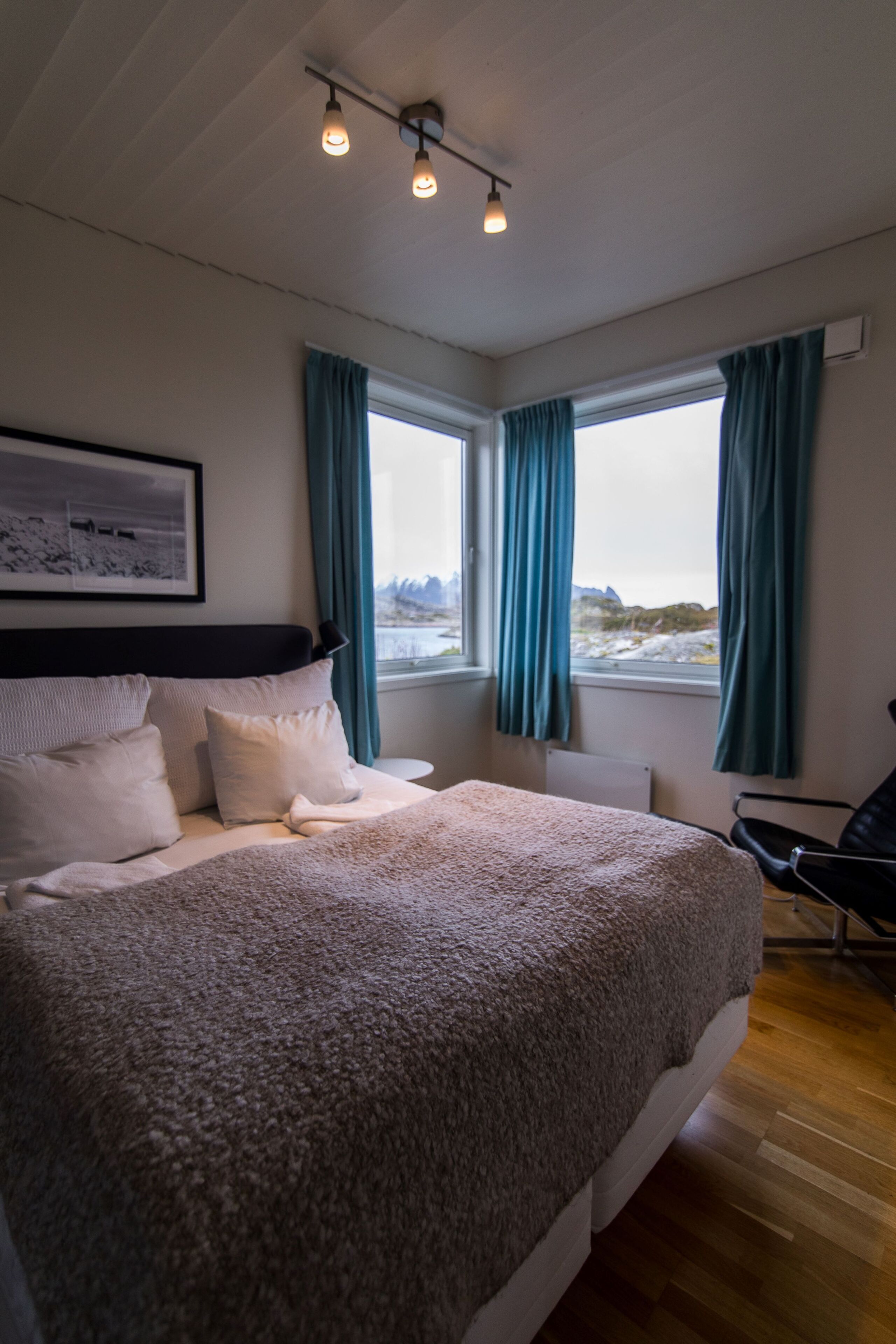 A bedroom with a large bed, a chair, and a window with curtains.