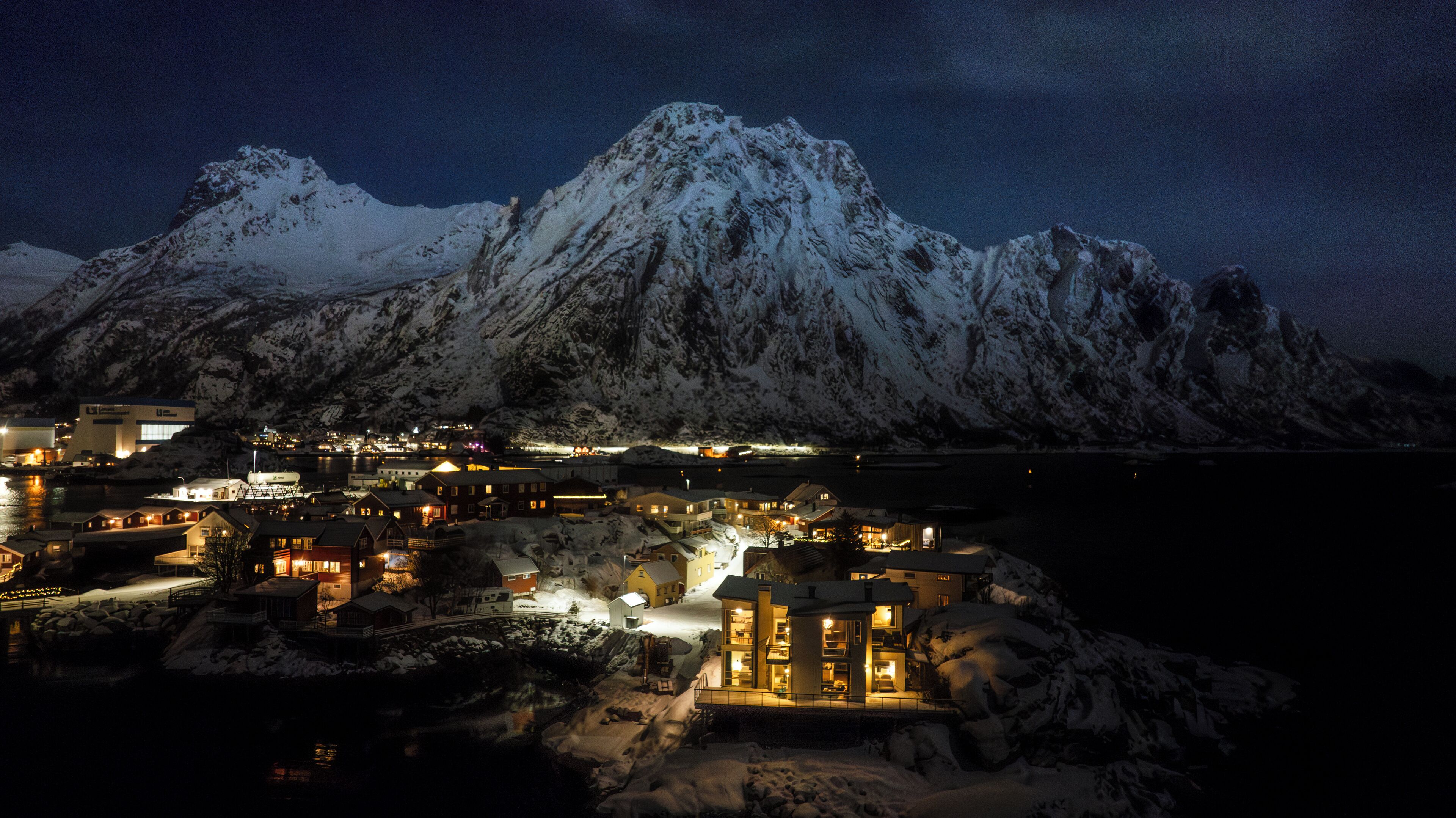 A snow-covered mountain with a lit-up town in the foreground.