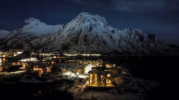A snow-covered mountain with a lit-up town in the foreground.