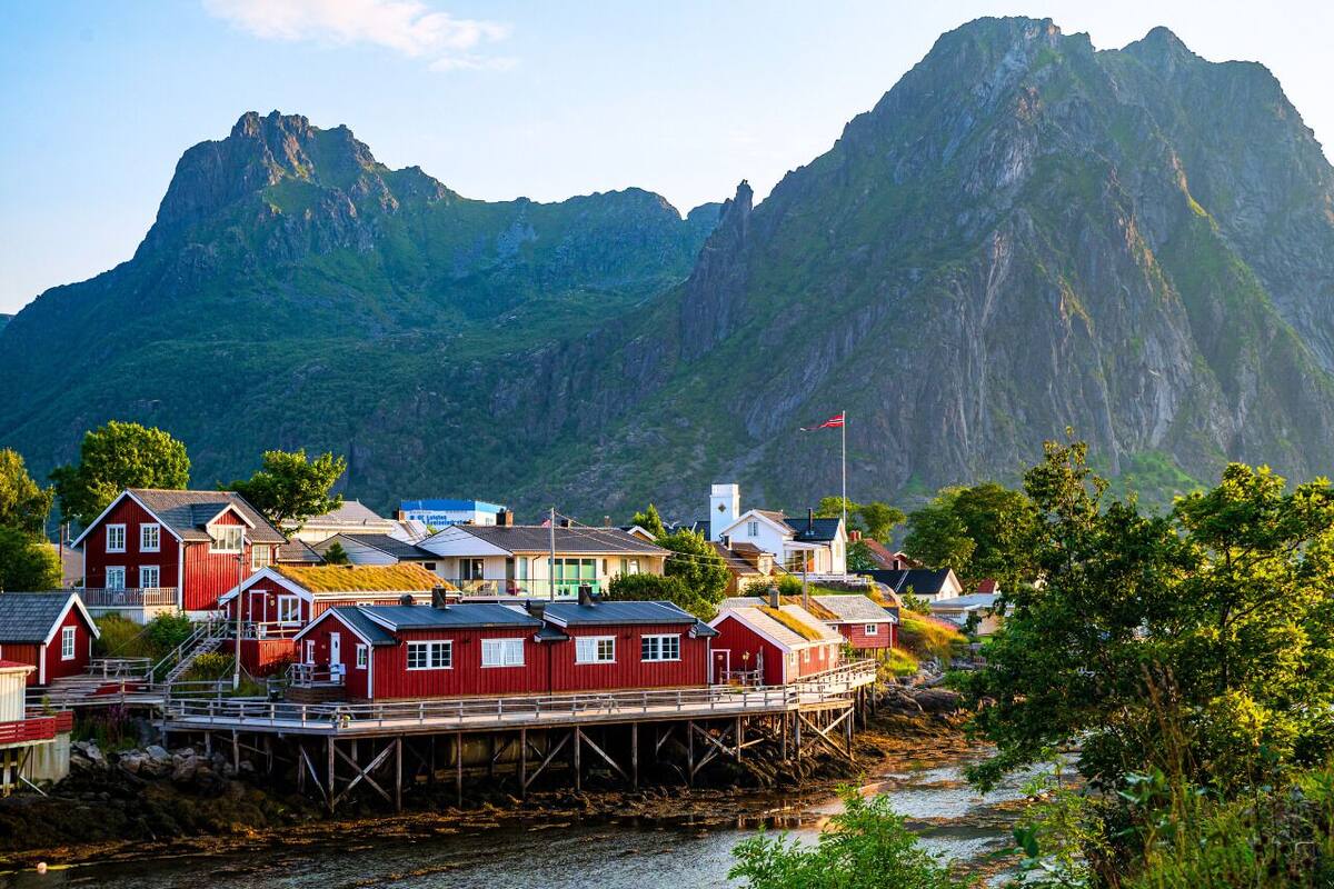 A coastal village with red houses, a pier, and a mountain in the background.