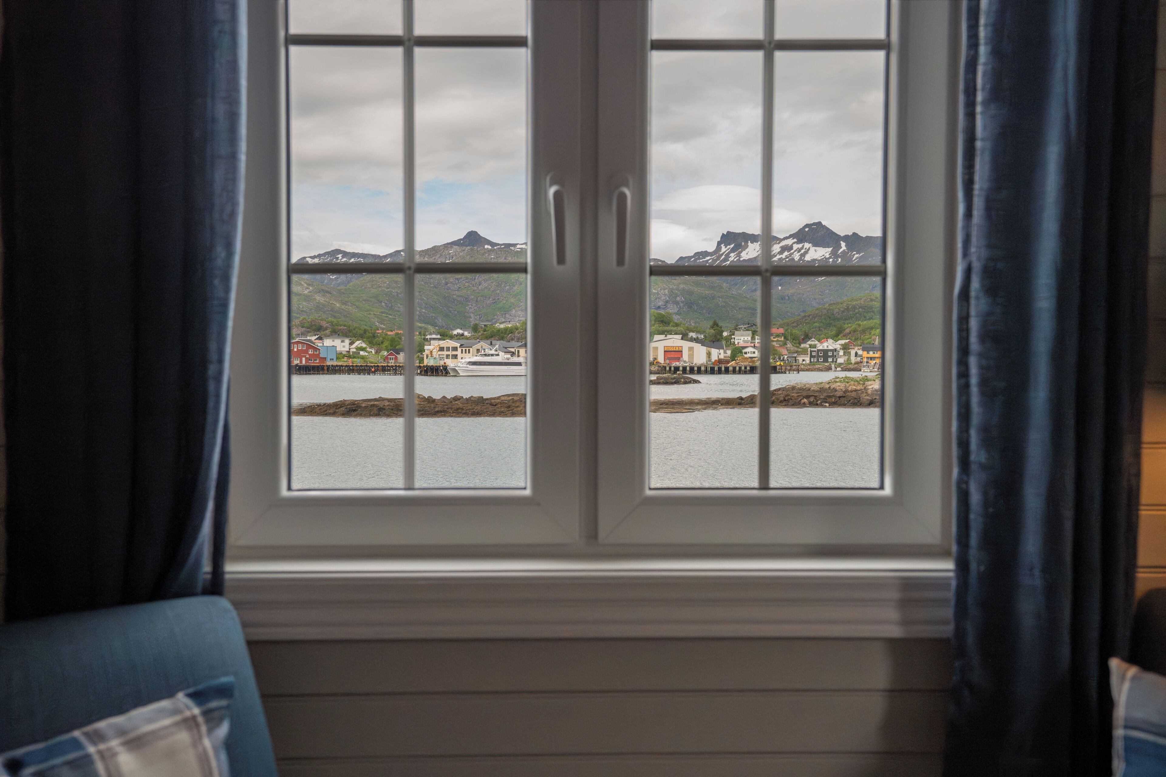 Een uitzicht op een stad en bergen vanuit een raam.