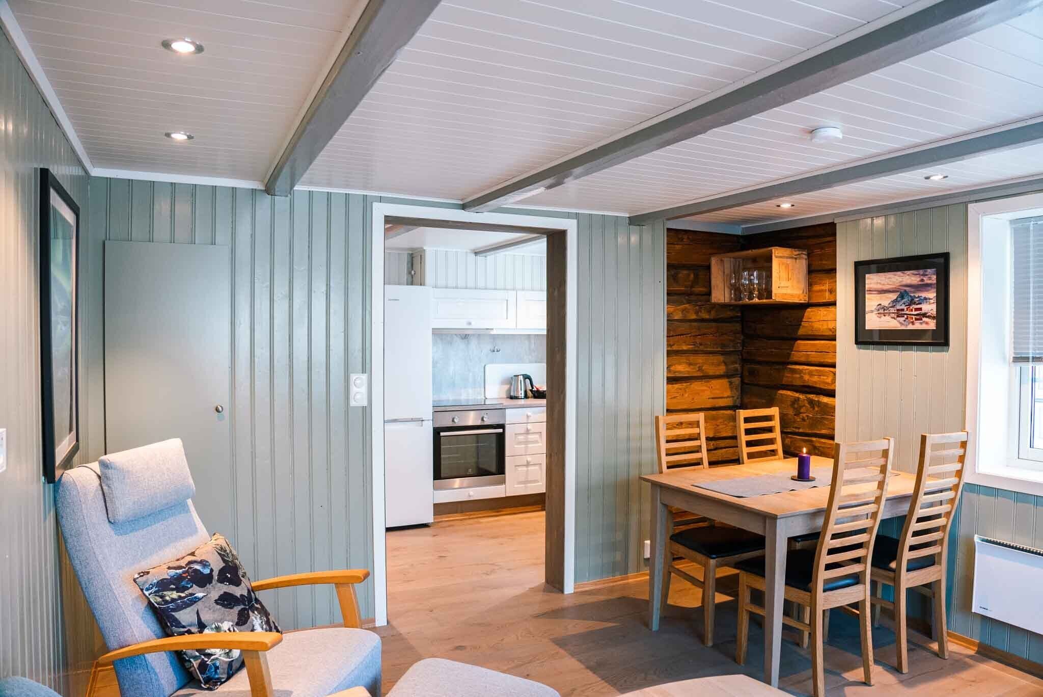 Ein gemütliches Interieur mit Essbereich, Holzwänden und einer durch eine offene Tür einsehbarer Küche.