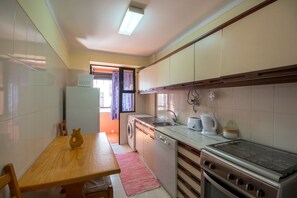 Une cuisine compacte comprenant une table à manger, un lave-linge, un lave-vaisselle, une cuisinière et un four à micro-ondes.
