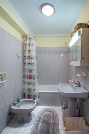 A bathroom with a bidet, a sink, a bathtub, a shower curtain with animal prints, and a mirror above the sink. - Apartment São Pedro do Mar with Terraces, A/C & Wi-Fi (Quarteira)