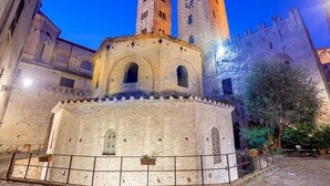 Un edificio storico con un cortile centrale, due torri e un muro fortificato.