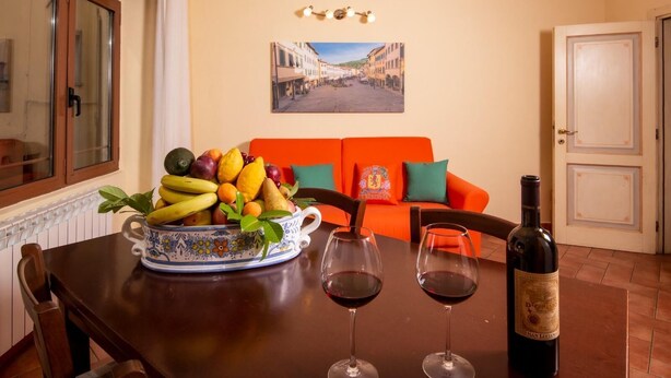 A dining table with a fruit bowl, two wine glasses, and a wine bottle. - One Bedroom Apartment (Bibbiena)