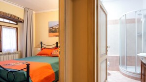 Habitación de hotel con cama, ventana con cortinas, un cuadro en la pared y zona de ducha.