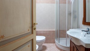 A bathroom with a toilet, a shower enclosure, and a sink. - One Bedroom Apartment (Bibbiena)