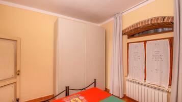 Ein Zimmer mit einem Bett, einem Heizkörper und einem Fenster mit Vorhängen.