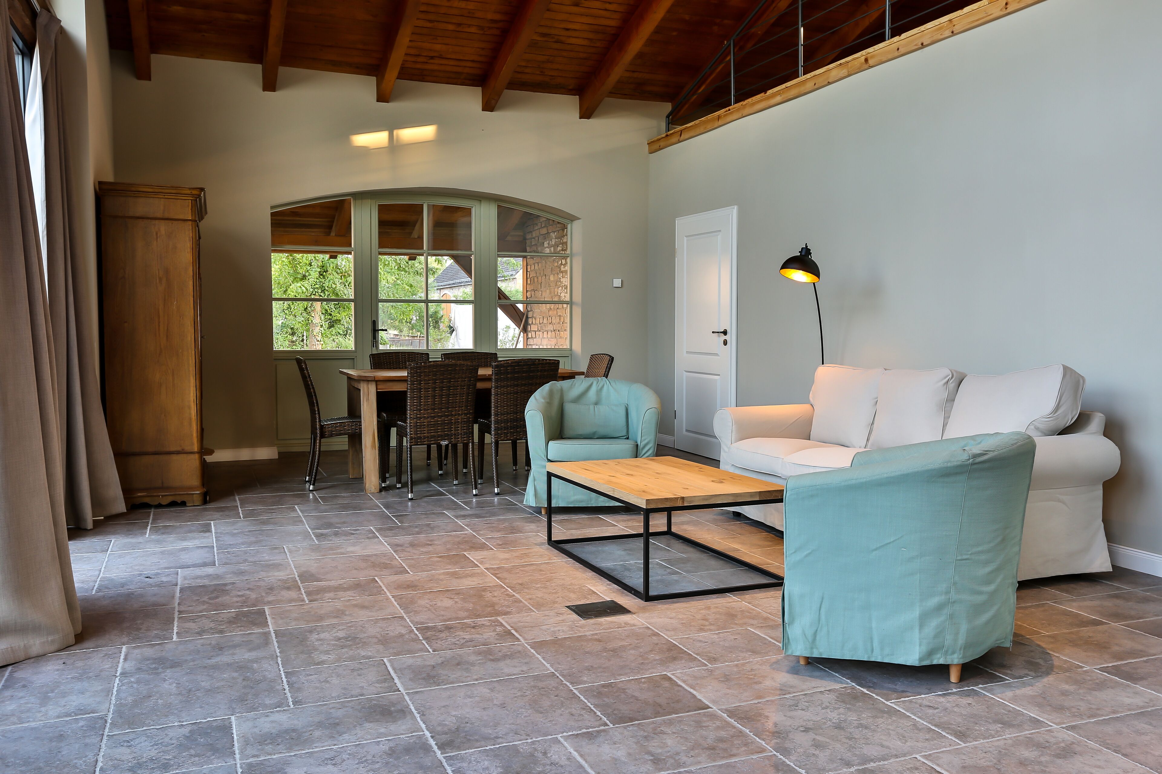 Un espacio habitable amplio con techo de madera, una mesa de comedor y dos sofás.