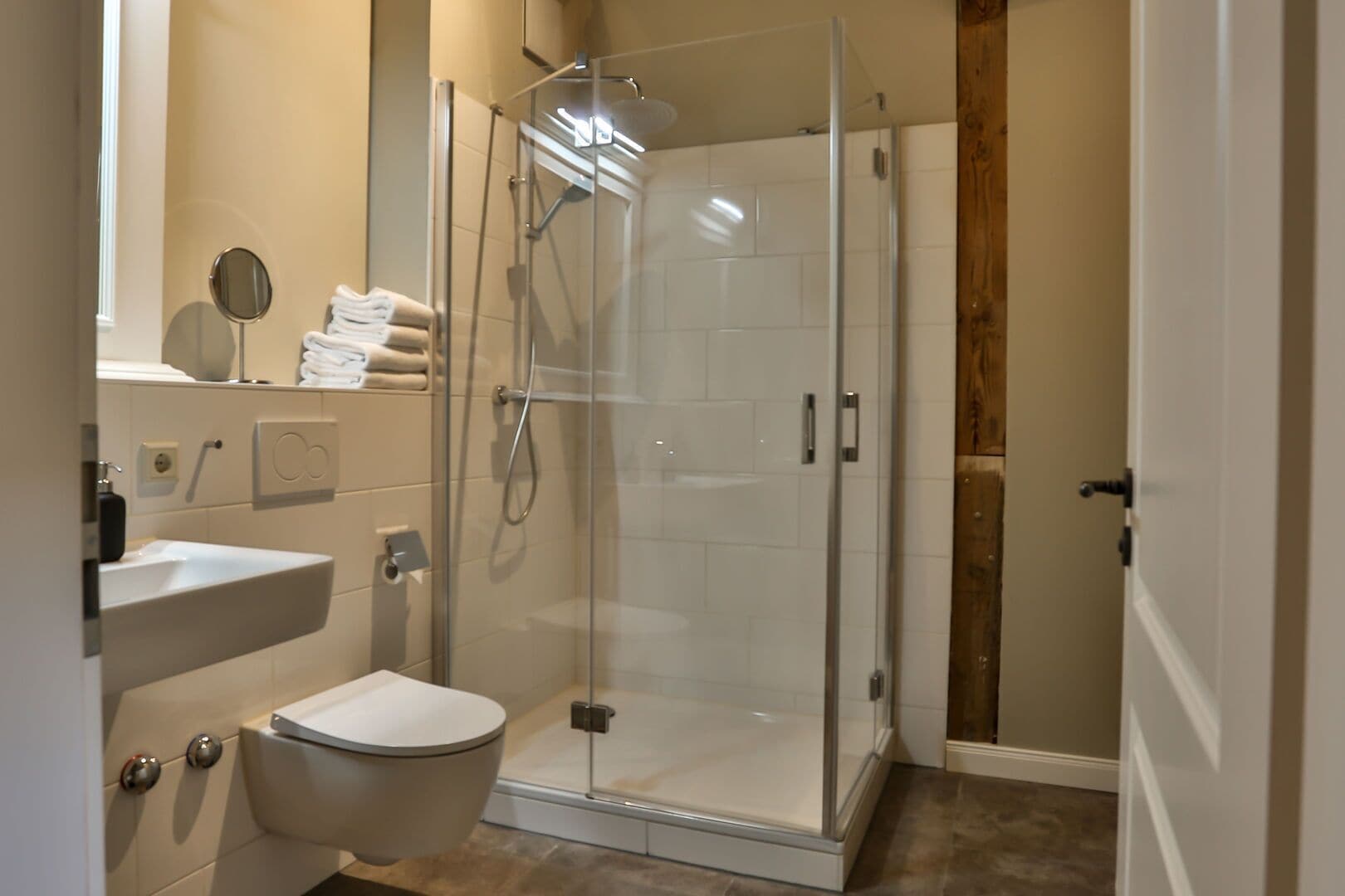 Un baño moderno con ducha acristalada, inodoro y lavamanos.