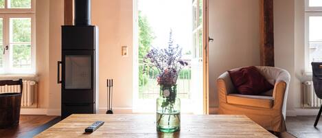 A wooden table with a remote control and a vase of flowers.