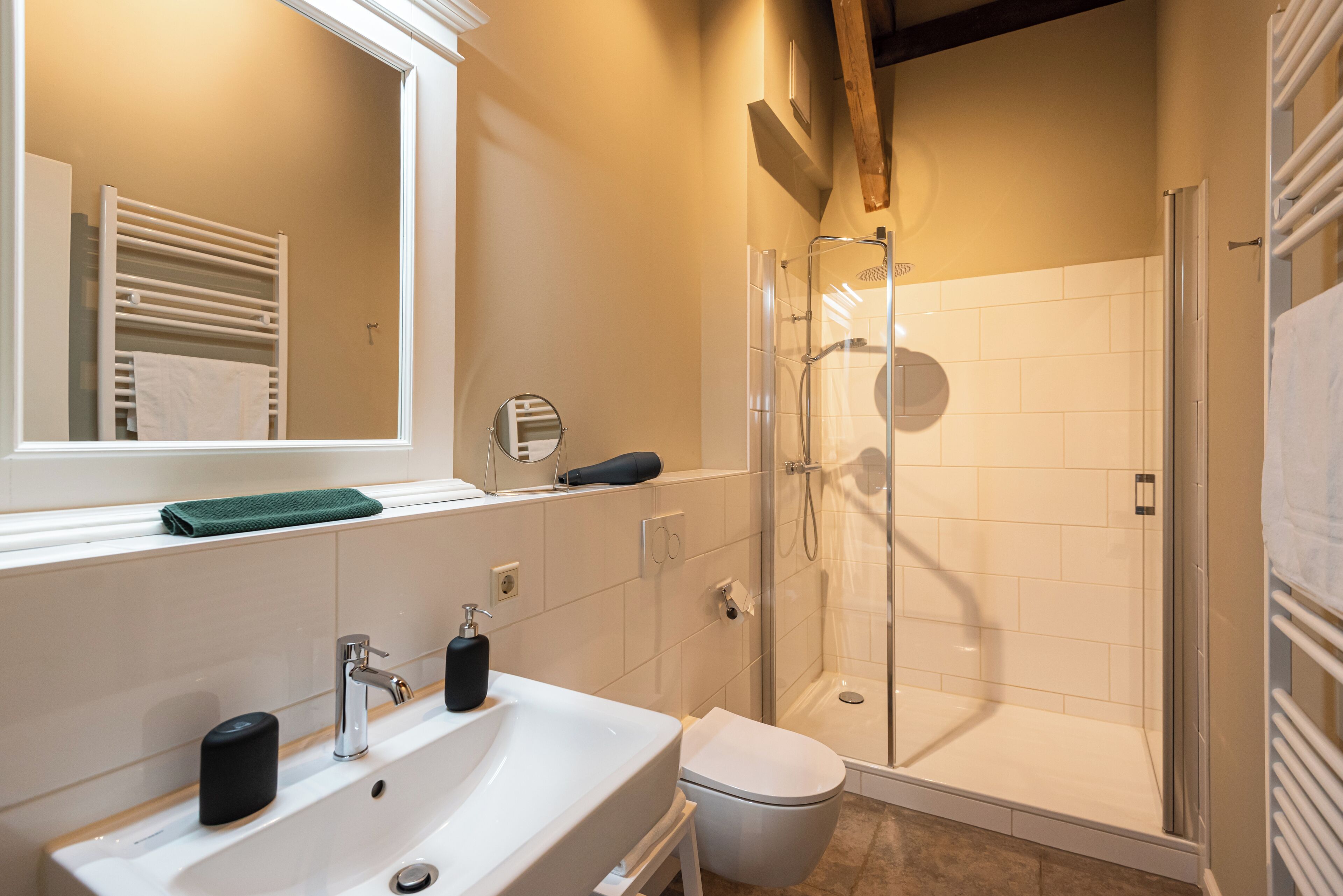 A modern bathroom with a white sink, a mirror, a glass-enclosed shower, and a towel rack.