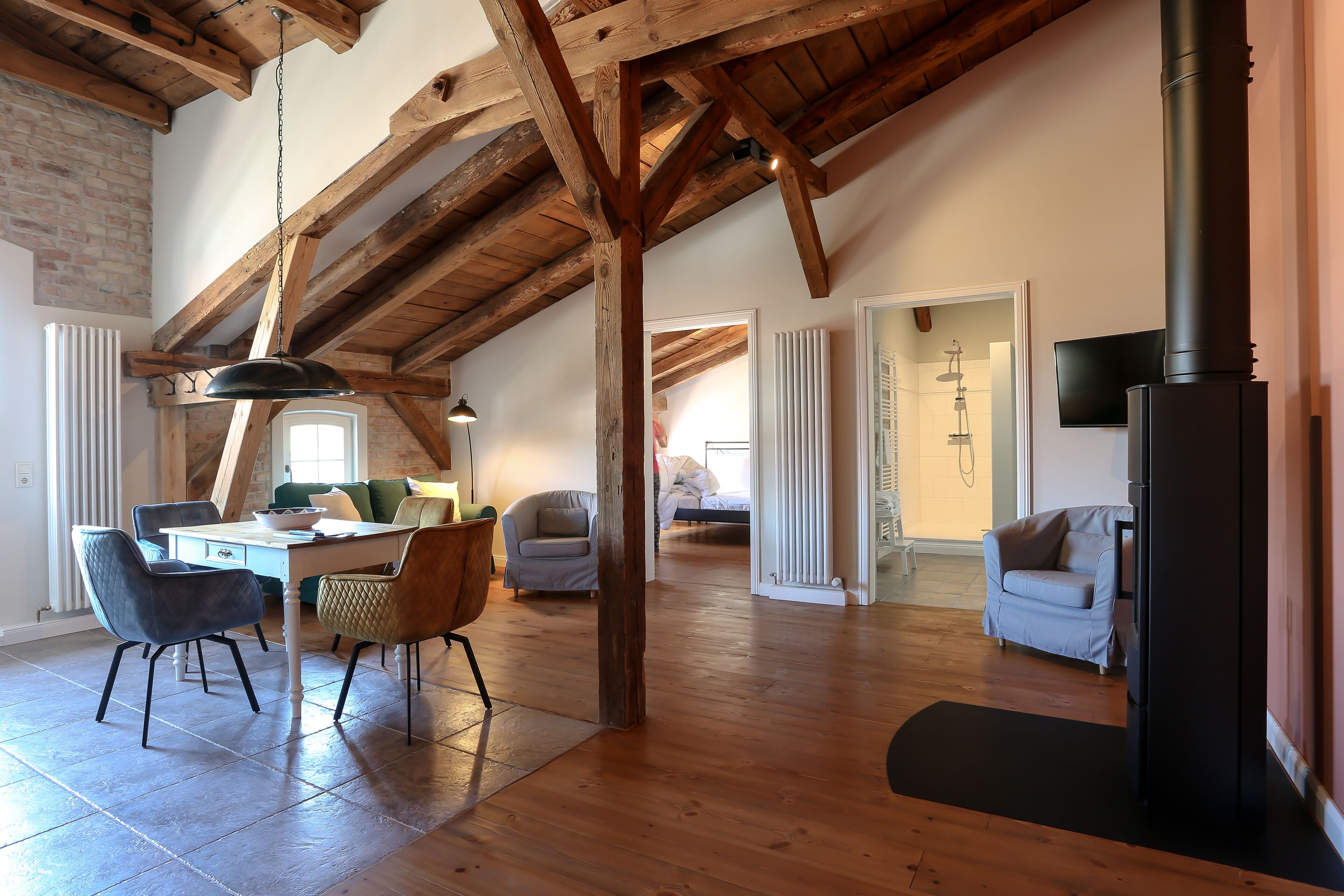 Un loft espacioso con vigas de madera a la vista, un comedor con sillas modernas, una chimenea y una zona de estar acogedora con sofás.