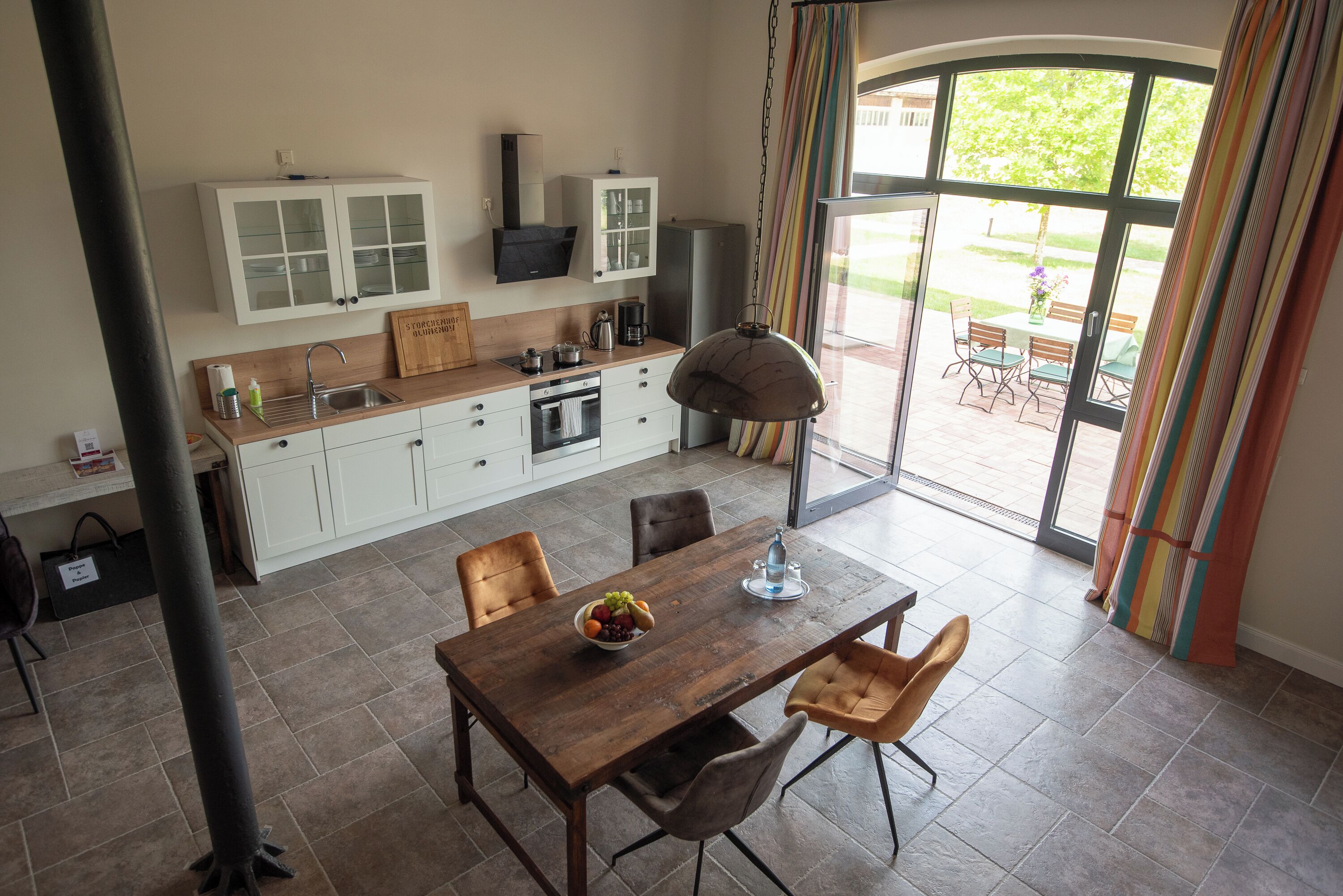 A modern kitchen with white cabinets, a wooden countertop, and a dining area with a table and chairs.