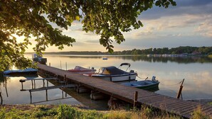 A wooden dock with boats, a calm lake, and a distant shoreline.