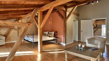 Un dormitorio tipo loft con vigas de madera a la vista, una cama, una silla y una mesa con botellas y vasos.