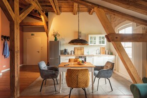 Un comedor con una mesa de madera, cuatro sillas y una lámpara colgante.