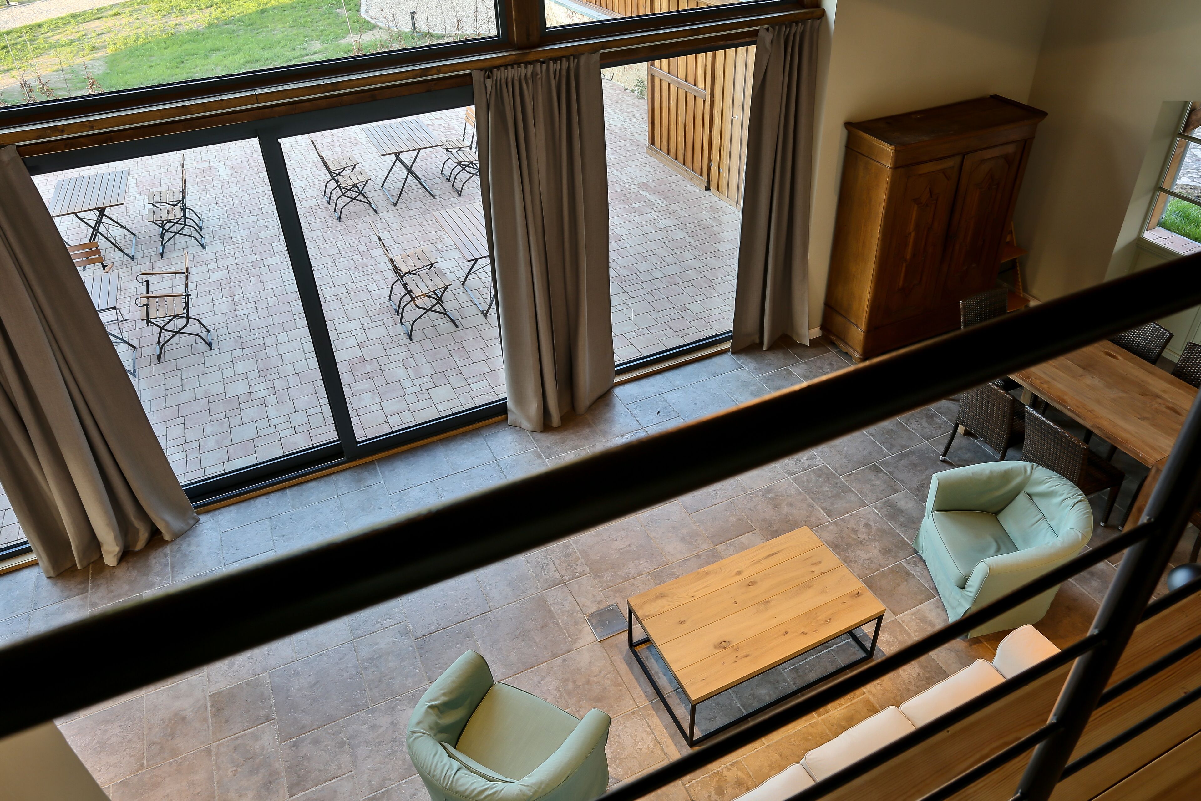 Un ampio balcone con pavimento piastrellato, sedute da esterno e un armadietto in legno.